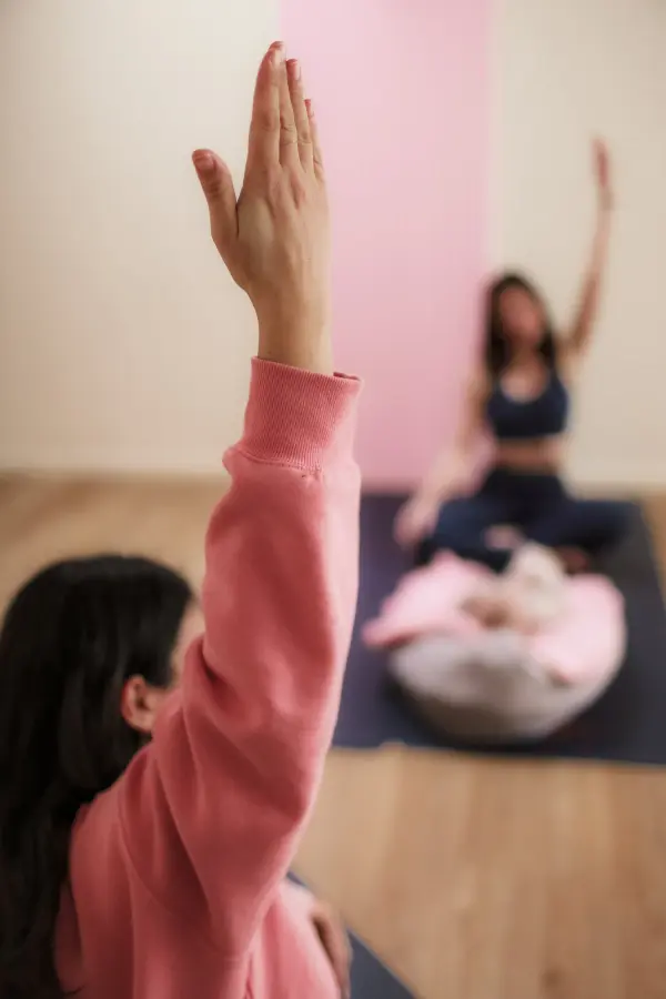 Une femme lève la main lors d'une séance de yoga.